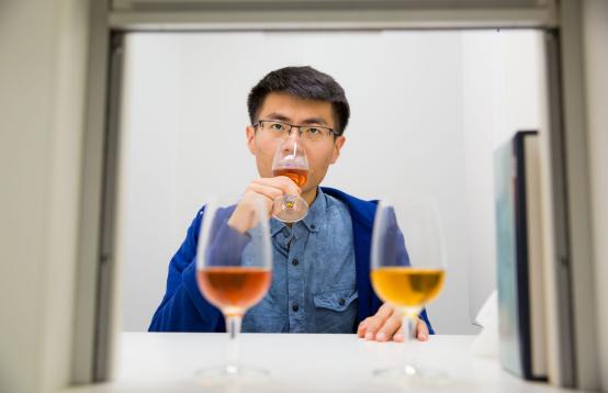 Man wearing glasses and a black shirt tasting wine