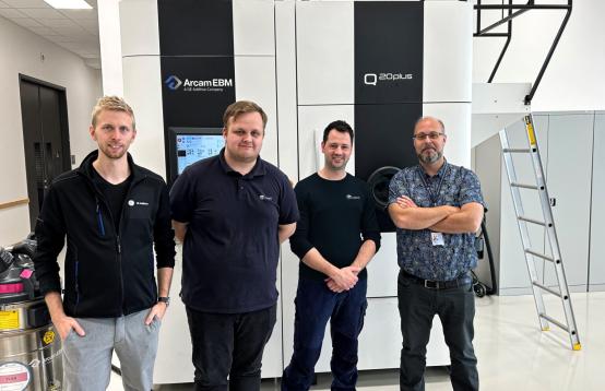 4 people standing in front of industrial machines