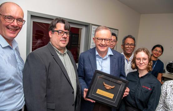 Six persons standing around the Hon Anthony Albanese holding an award