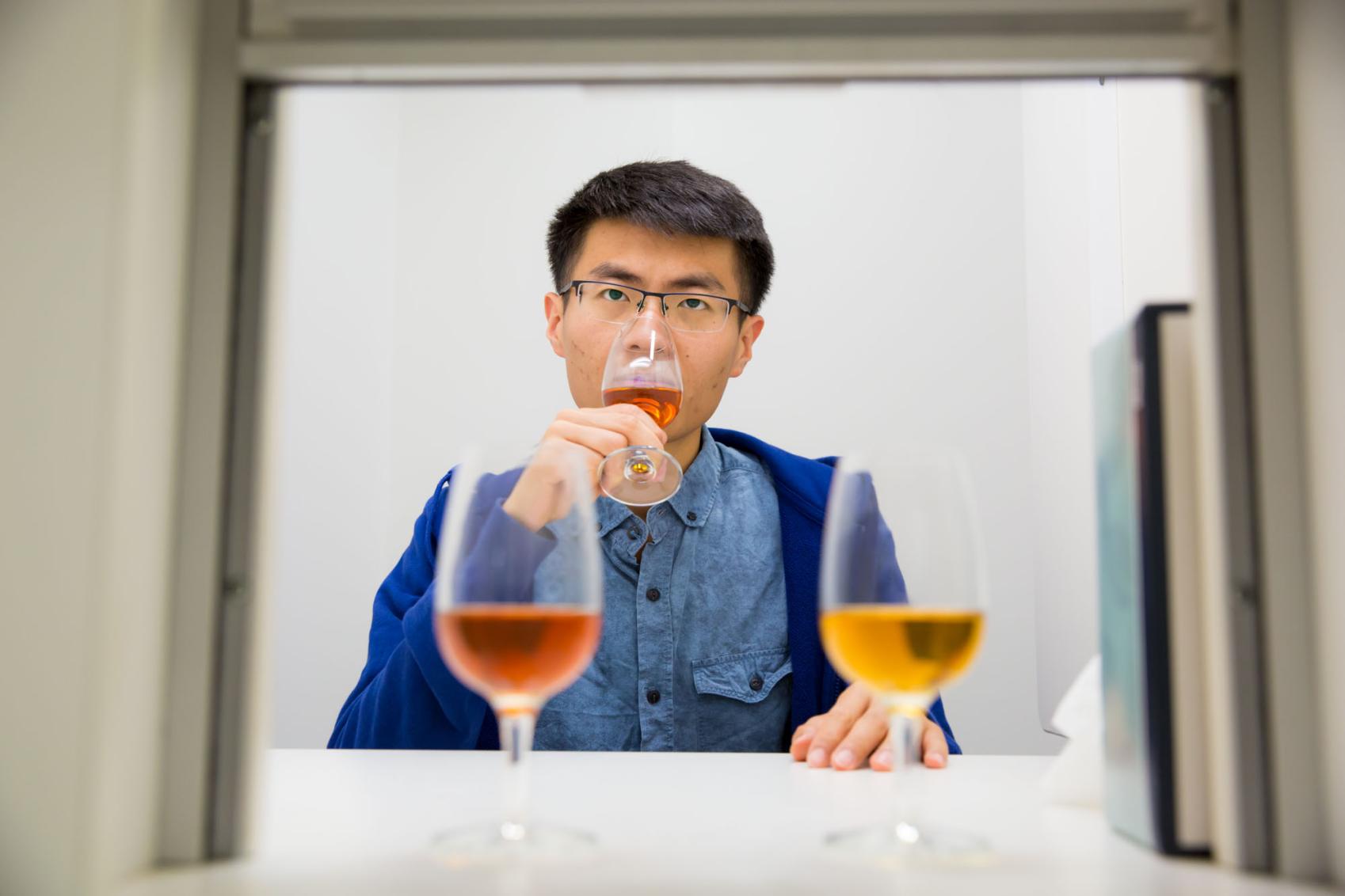 Man wearing glasses and a black shirt tasting wine