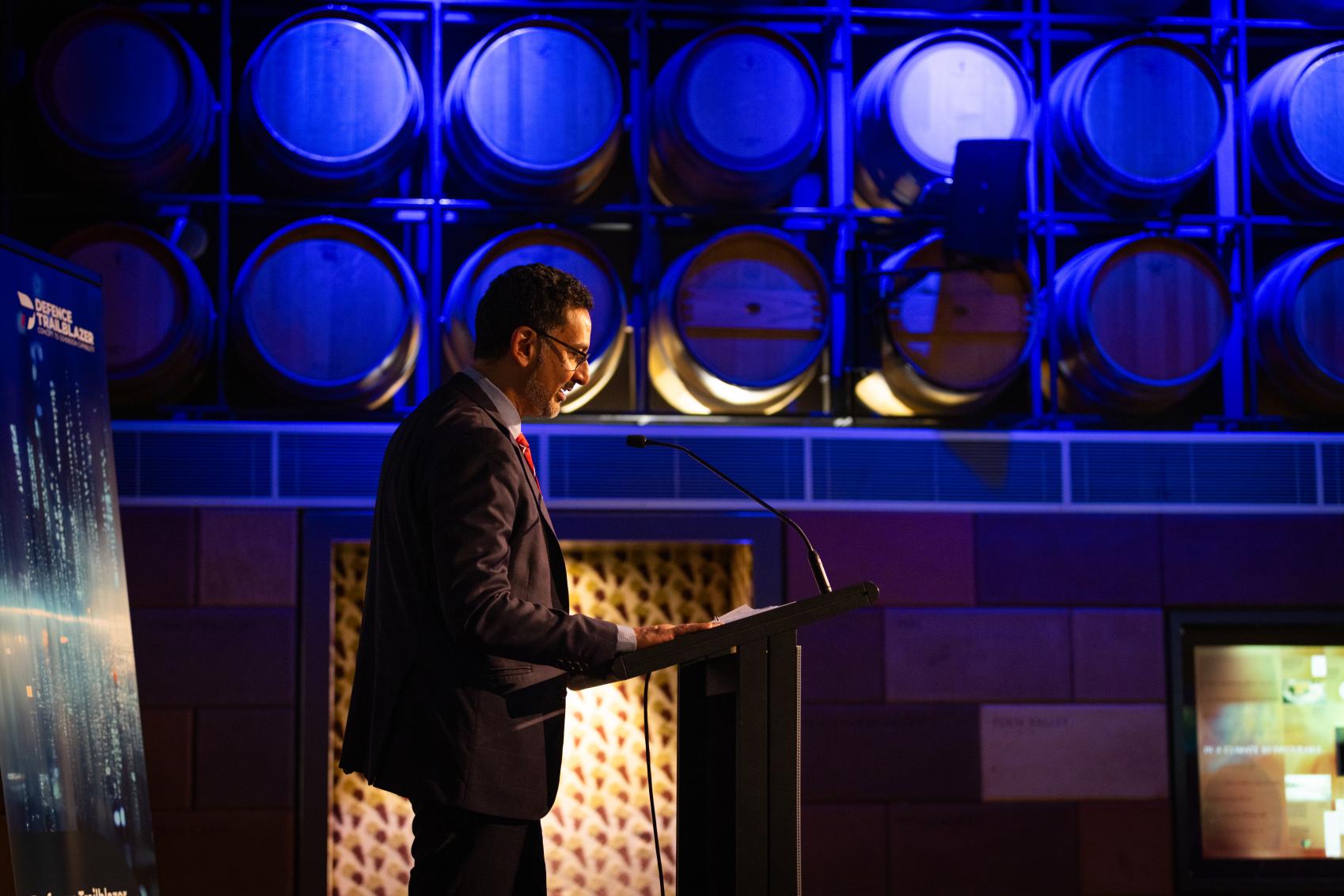 Man wearing a suit presenting from a podium