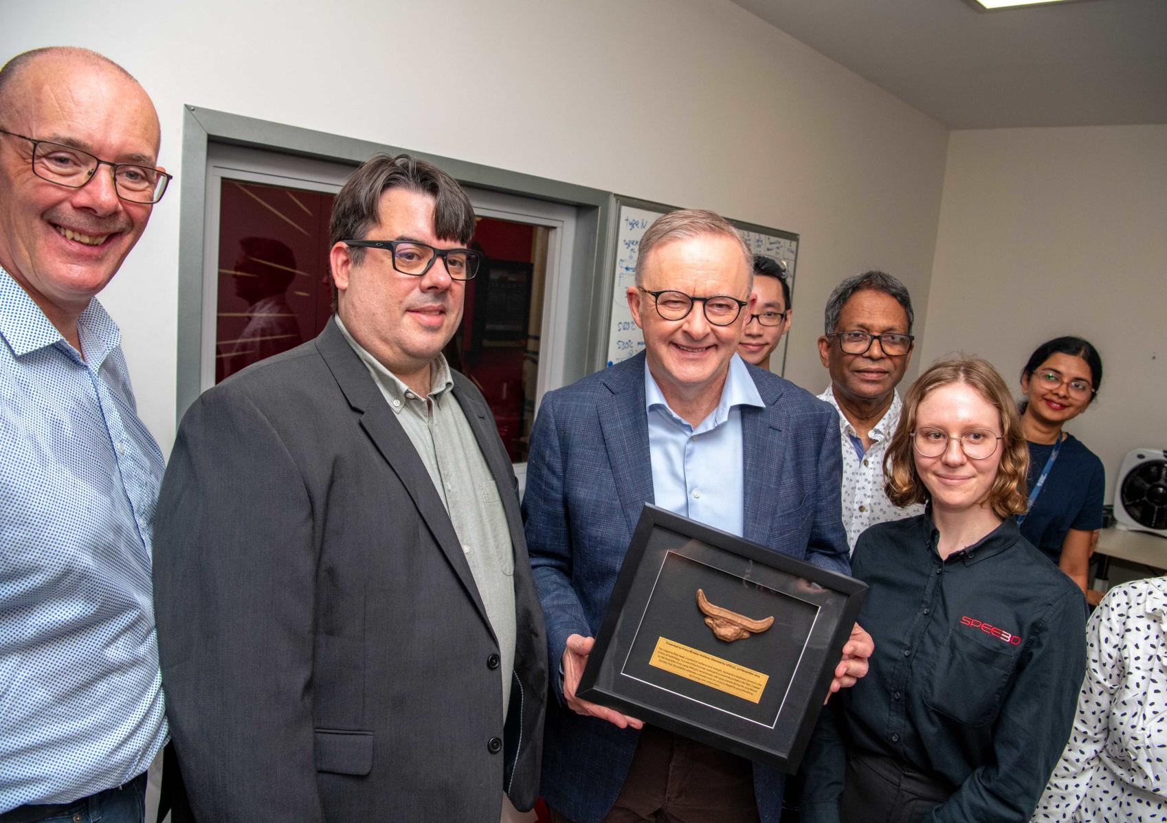 Six persons standing around the Hon Anthony Albanese holding an award