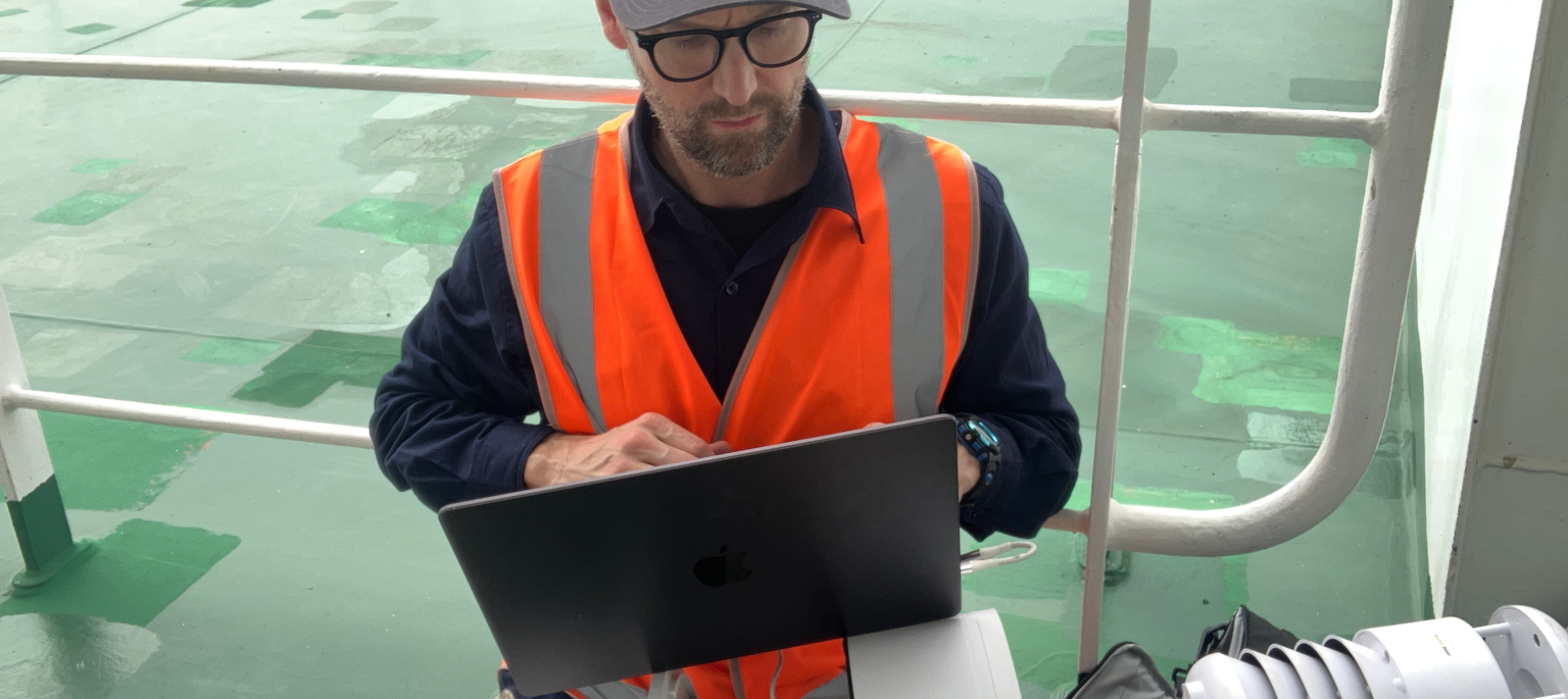 Man outside looking at computer laptop